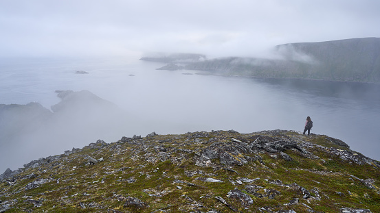 A female hiker in the mountains with a foggy landscape in Norway, Norkapp