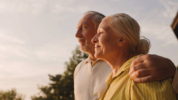 улыбающаяся пожилая пара, обнимающаяся на свежем воздухе, наслаждающаяся видом на город на закате, семейная любовь - aging process morning outdoors horizontal стоковые фото и изображения