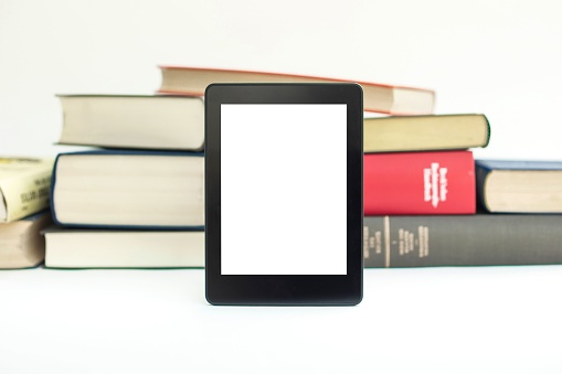 A close-up of an E-book device with books in white background