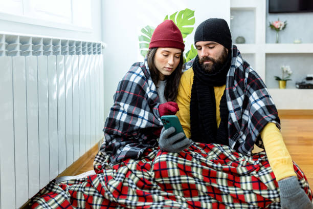 istock A young couple is suffering from a cold temperature during an energetic crisis and trying to warm up near the radiator. 1461577417