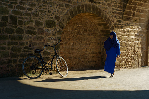 Morocco. Essaouira. A woman wearing djellaba walking in a street of the medina