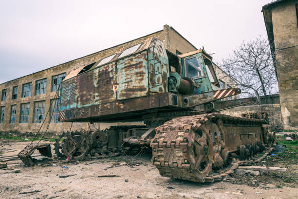 An Abandoned rusty excavator at an abandoned factory with a light sky