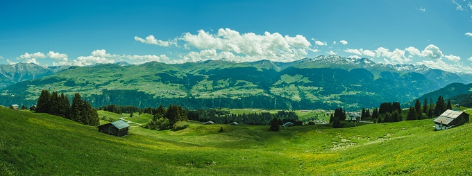 A panoramic shot of a house in a field on the foot of Brigels Breil Mountains in Grisons, Switzerland