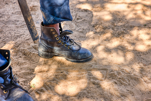 detail of army boot worn by a African man in a village in Botswana, sandy ground texture