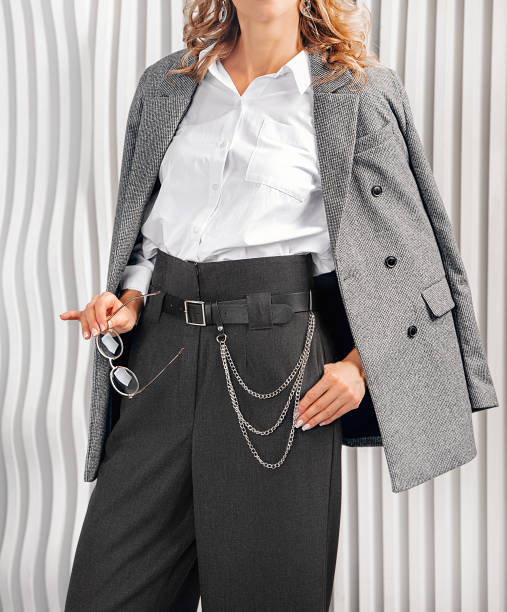 Women's Business suit. Gray jacket, high-waisted palazzo trousers, black belt with silver chain. White shirt with chest pocket. straight leg pants stock pictures, royalty-free photos & images