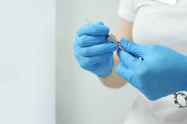 woman holding medical injection syringe in her outstretched hand towards the camera. selective focus, copy space blue glove decoration on the hand of a female dentist - surgical glove human hand holding capsule imagens e fotografias de stock