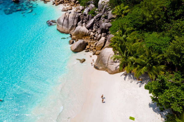 young men on a white beach with turquoise colored ocean, Drone view from above at Anse Lazio beach Praslin Island Seychelles young men on a white beach with turquoise colored ocean, Drone view from above at Anse Lazio beach Praslin Island Seychelles. praslin island stock pictures, royalty-free photos & images