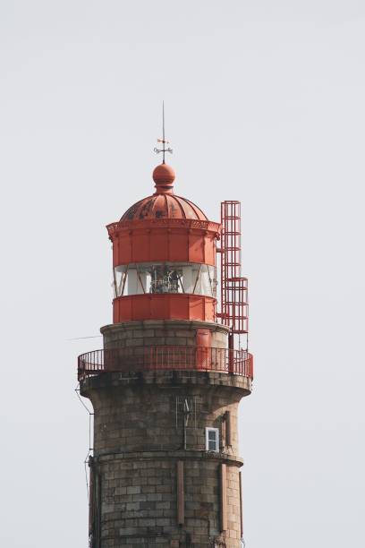 istock Front facade of an old red lighthouse against a cloudy sky 1461587159