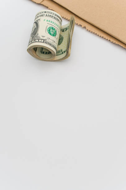 istock isolated US dollar banknotes roll on a white and brown paper background 1461588923
