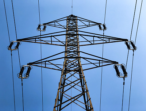 A low angle shot of a transmission tower on a blue sky background