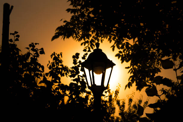 A silhouette of a lamp on a bright sunset sky background