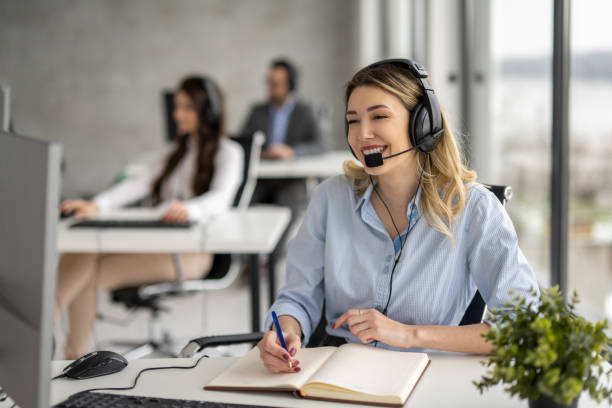 istock Young blonde woman working in call center, talking to client and taking notes to notebook. 1461590934