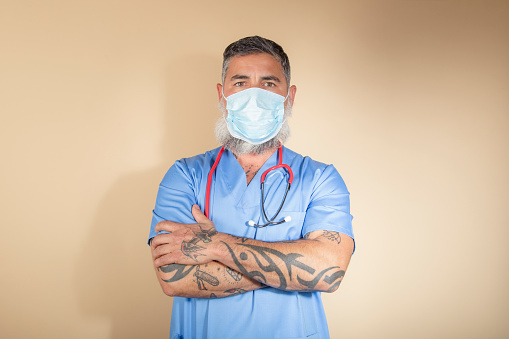 Cropped shot of Caucasian male nurse standing with arms crossed on a light background.
