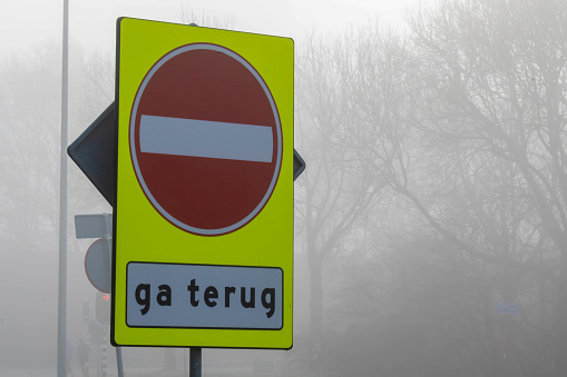 A stop road sign near the park on a foggy day