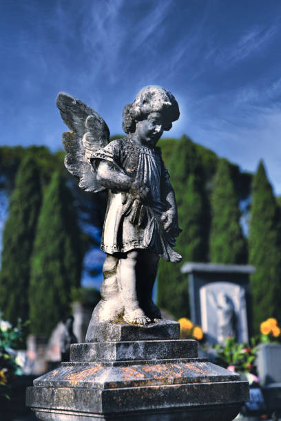 istock Selective focus high contrast shot of a stone angel statue at a graveyard with tall trees around 1461593794