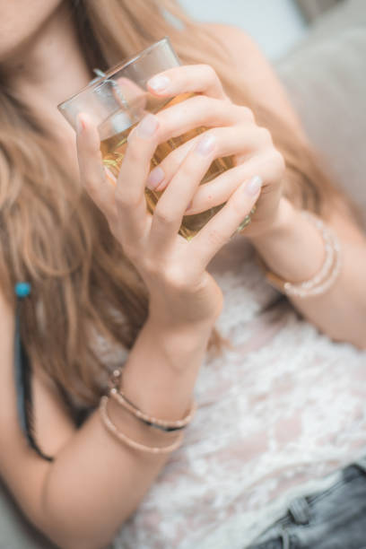 Vertical shot of a female holding a glass full of tea with both hands