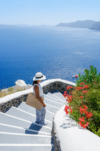Asian woman visit Oia Santorini Greece on a sunny day during summer with whitewashed homes and churches, Greek Island Aegean Cyclades