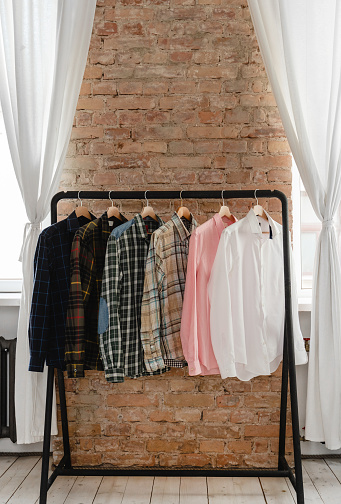 Clothing rack with a variety of male shirts all hanging neatly on wooden hangers