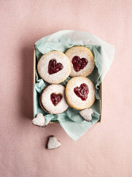 Shortbread cookies in shape of heart in box on pink background, Linz cookie (jam shortbread buiscuit), Valentines heart cookies, Cookie with jam, Packaging Linzer Christmas cookies to make a present stock photo