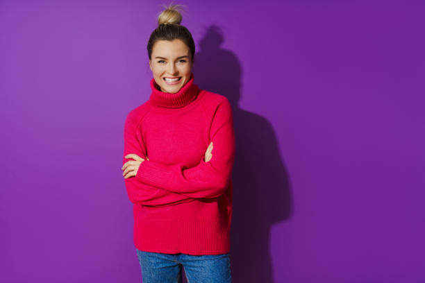 Young woman wearing warm and cozy polo neck sweater against purple background Portrait of young woman wearing warm and cozy polo neck sweater against purple background mock turtleneck stock pictures, royalty-free photos & images