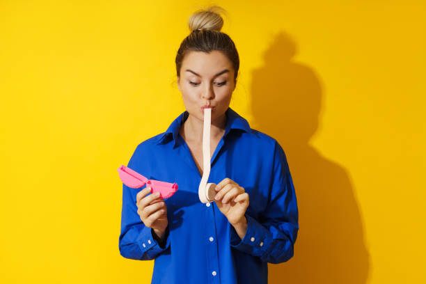 mujer joven probando chicle sobre fondo amarillo - chewing gum women bubble blowing fotografías e imágenes de stock