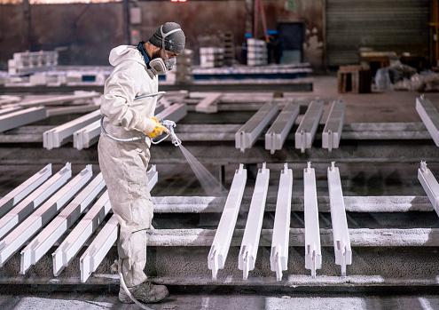 Man painting metal in factory