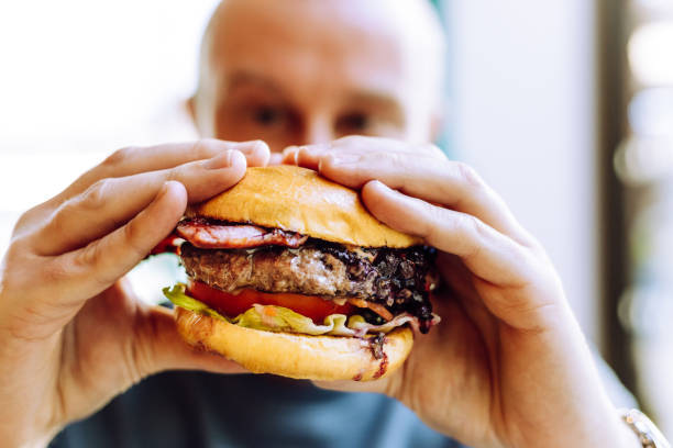 istock Man holding delicious fresh flame grilled burger in restaurant 1461608144