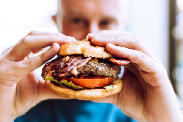 istock Man holding delicious fresh flame grilled burger in restaurant 1461608151