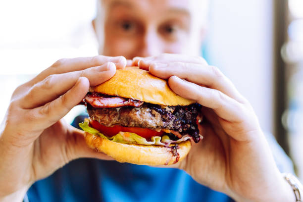 istock Man holding delicious fresh flame grilled burger in restaurant 1461608160
