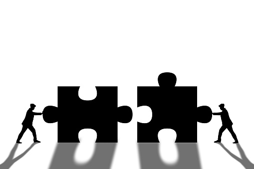 Business teamwork concept, two businessman are assembling the puzzle pieces