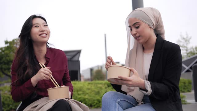 Multiracial business women eating takeaway lunch break outdoor outside the office
