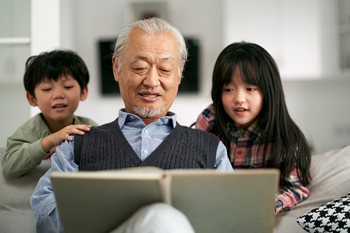 senior asian grandfather having a good time with two grandchildren at home