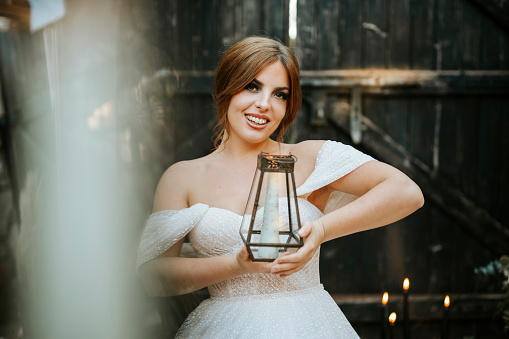 Portrait of beautiful bride holding lantern in rustic background
