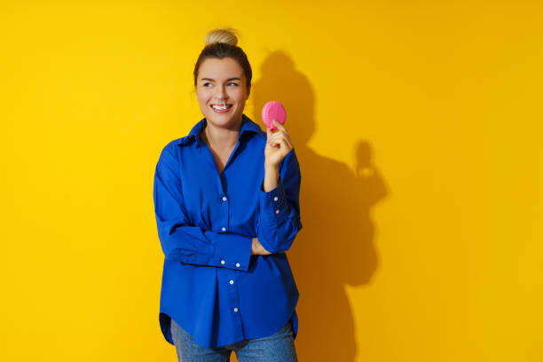 mujer feliz soplando una burbuja con chicle sobre fondo amarillo - chewing gum women bubble blowing fotografías e imágenes de stock