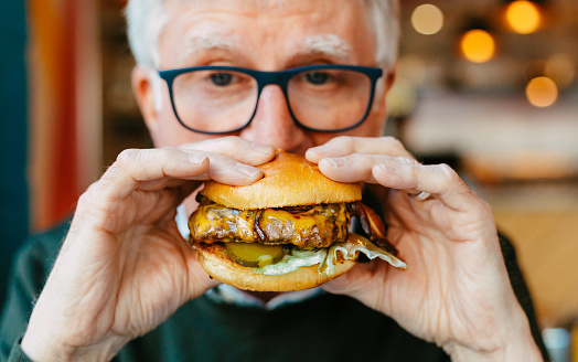 Man holding delicious fresh flame grilled burger in restaurant