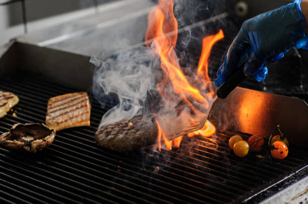 istock Closeup image of chief cook holding roasted meat at open fire grill kitchen background. 1461616292