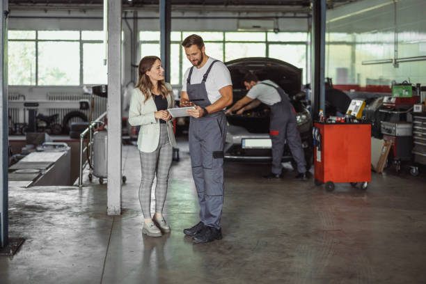 Car Mechanic and Customer Using Digital Tablet Car mechanic and female manager cooperating while working on touchpad in auto repair shop auto repair shop mechanic digital tablet customer stock pictures, royalty-free photos & images