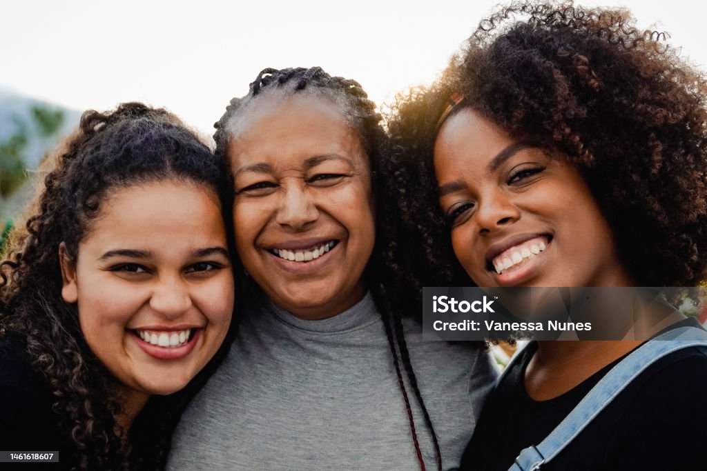 Portrait of happy African mother and daughters having fun outdoor looking at camera - Love family concept - Focus on right girl Women Stock Photo