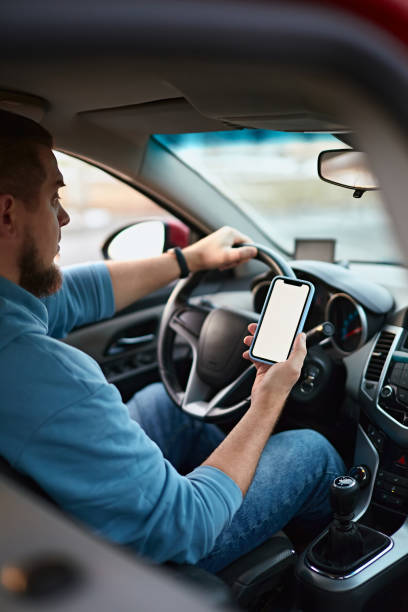istock Man driver using mobile phone screen blank mockup on the road while driving a car 1461619284