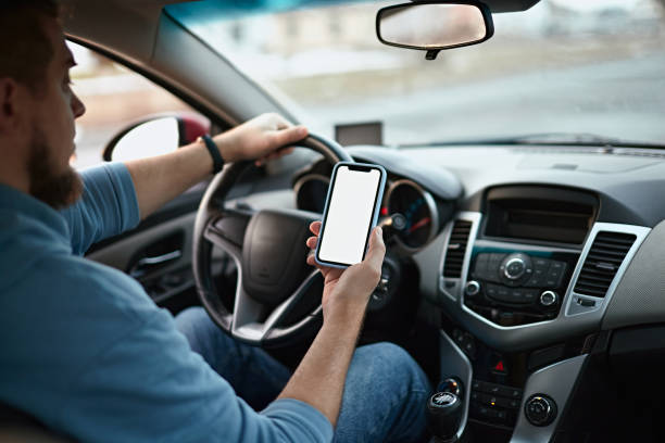 istock Man driver using mobile phone screen blank mockup on the road while driving a car 1461619292