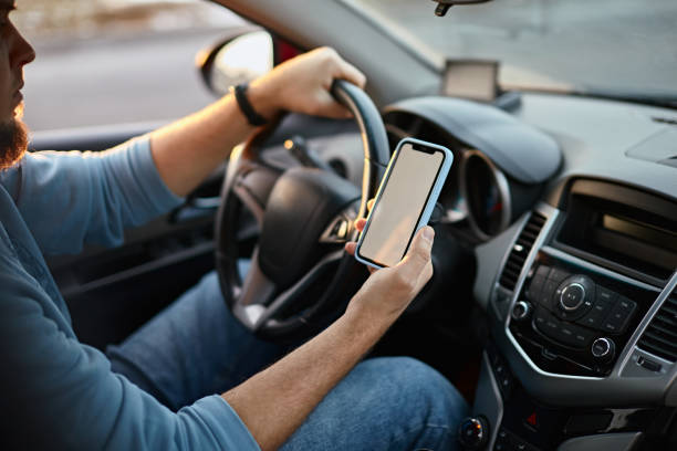 istock Man driver using mobile phone screen blank mockup on the road while driving a car 1461619306