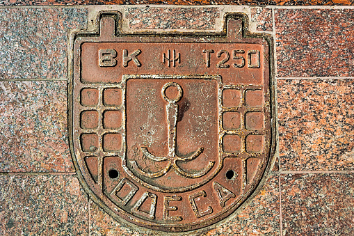 Odessa, Ukraine - SEP 20, 2021: Typical sewer manhole in Odessa with an inscription and a coat of arms, Ukraine