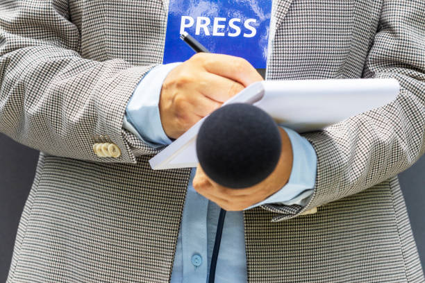 istock Journalist with press pass or media accreditation at news event, holding microphone, writing notes 1461622357