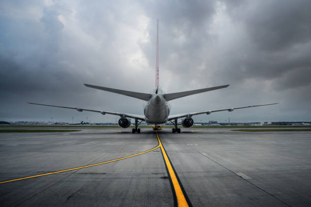 Passenger airplane at the airfield runway, rear view, dramatic sky
