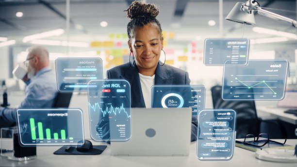 istock Female Project Manager Working on Computer in Office. Augmented Reality Corporate, Financial and Business App Icons Appear From Worker's Laptop. Productivity, Internet Connectivity and Online Concept. 1461627410
