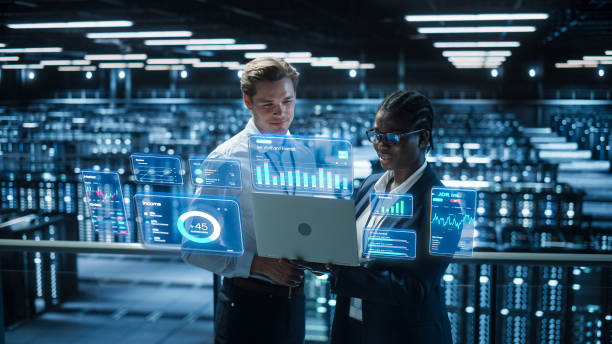 Technical Engineer and Project Administrator Using Computer in Modern Data Center Server Room Facility. Augmented Reality Productivity and Corporate Business Data Icons Appear From Worker's Laptop. Technical Engineer and Project Administrator Using Computer in Modern Data Center Server Room Facility. Augmented Reality Productivity and Corporate Business Data Icons Appear From Worker's Laptop. medical device engineering stock pictures, royalty-free photos & images