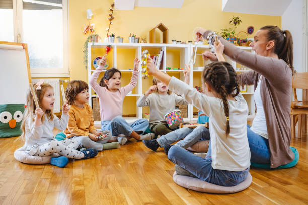 istock Kindergarten teacher with children sitting on the floor having music class, using various instruments and percussion. 1461629622