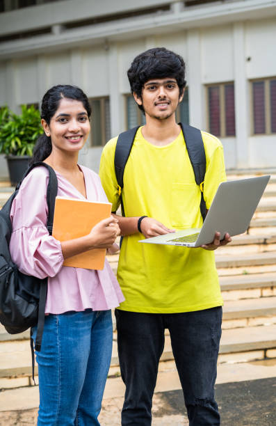 istock vertical shot of Happy smiling students with backpack holding laptop looking camera at college campus - concept of technology, friendship and skill development 1461630375