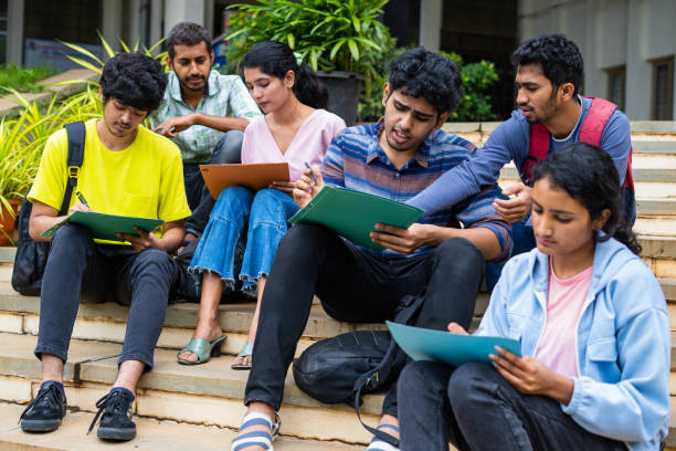 istock Group of students filling admission application form or preparing for exams on college campus by discussing eachother - concept of graduation, skill development and examination. 1461630476