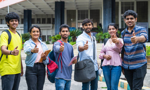 istock Confident students with backpack and books showing thumbs up by looking camera at college campus - concept of approval, education and development. 1461631347